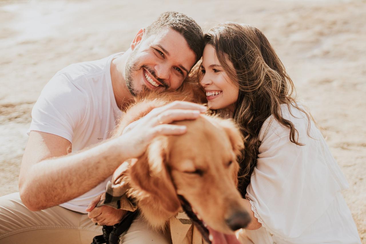 frases para fotos no instagram​ casal com cachorro sorri para foto em praia