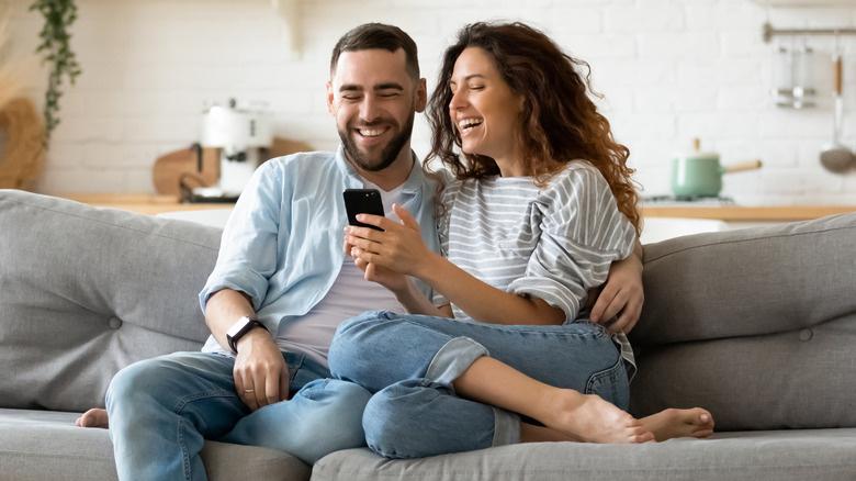 casal rindo no sofá
