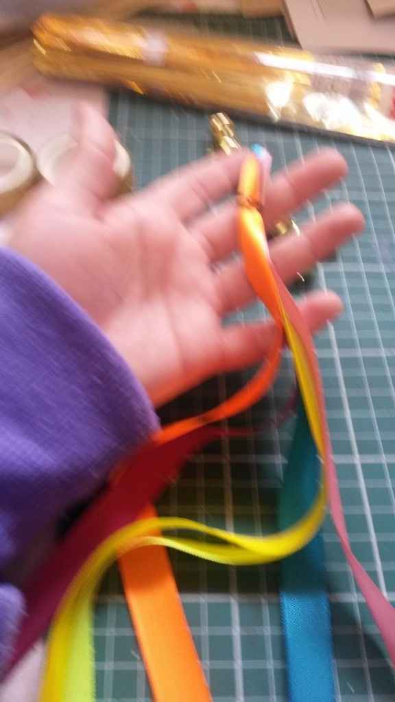Junta uma fita de cada cor (acho que eram 6 cores) e dá um jeito de prender na ponta do palito. Eu a