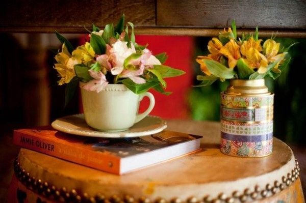 Xícaras e latinhas com flores, livros como suporte