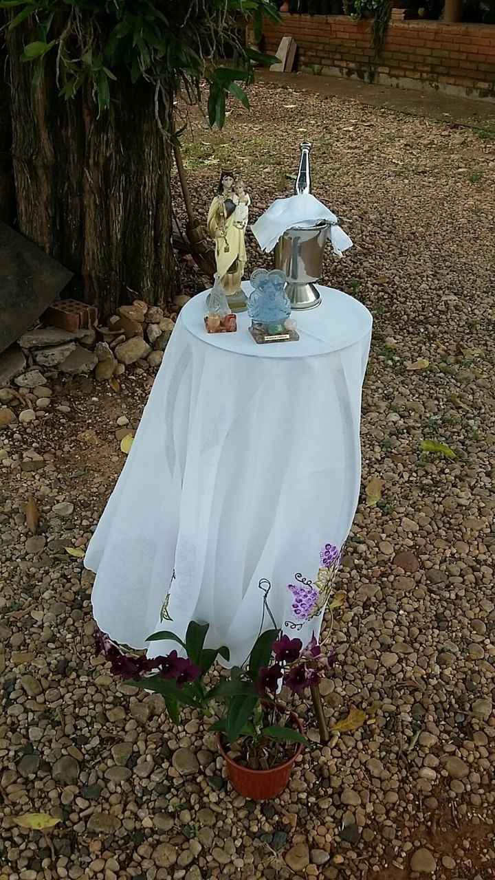 A mesinha de apoio do padre, com Nossa Senhora, a Sagrada Família e a Água
