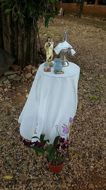 A mesinha de apoio do padre, com Nossa Senhora, a Sagrada Família e a Água