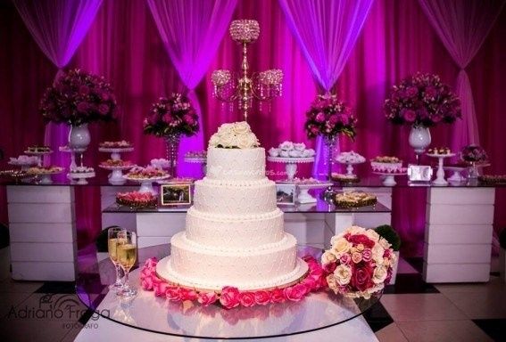 A mesa dos doces ao fundo e outra com o bolo