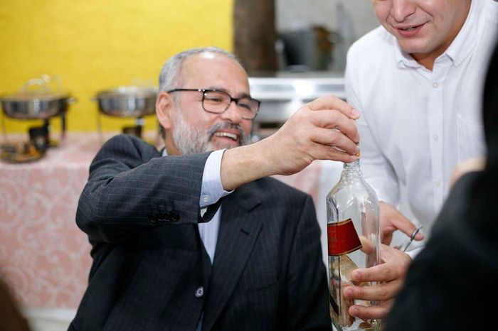 Os homens enchendo a garrafa com o corte da gravata