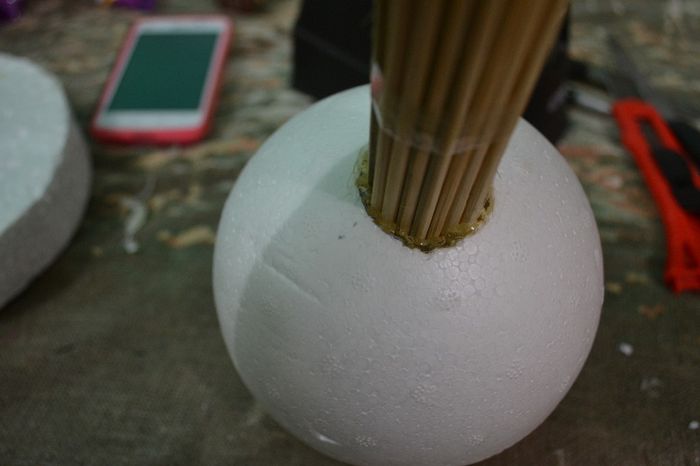 Passe fita durex para segurar os palitos. Faça um furo no isopor e cole com cola quente