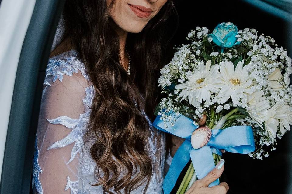 Noiva dentro do carro segurando buquê de flores brancas e azuis no dia do casamento