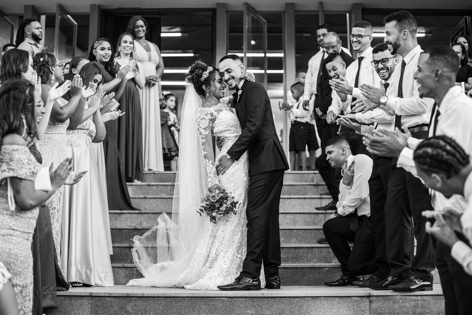 Casal se abraçando e convidados aplaudindo